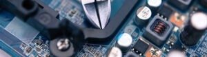 Gros plan d'un circuit imprimé avec composants électroniques et pince coupante métallique posée dessus.