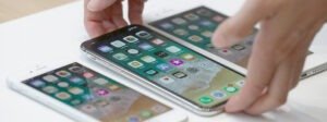 Un ensemble de smartphones sur une table, avec une main utilisant l'un d'entre eux.