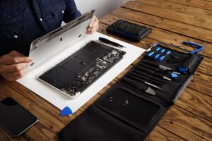 Réparation d'ordinateur portable avec outils et smartphone sur une table en bois.